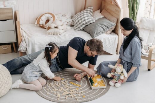 Father, mother, and daughter playing Scrabble.